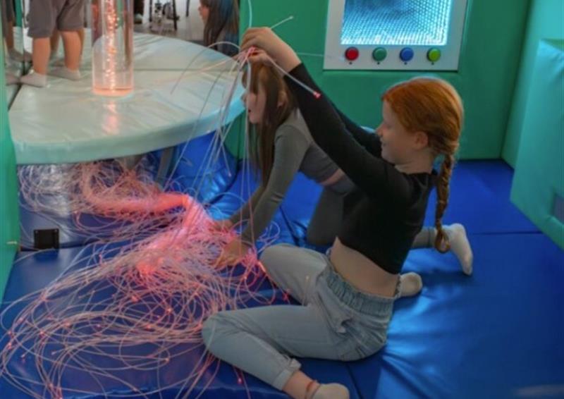 A young girl holding a string of lights and smiling
